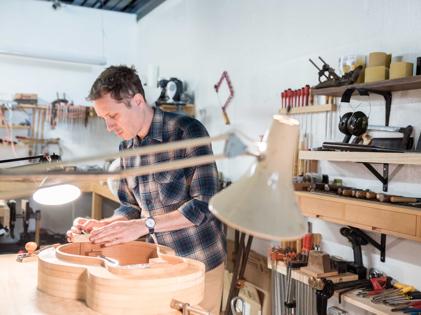 A young student building an electric guitar under a mentor luthier's guidance
